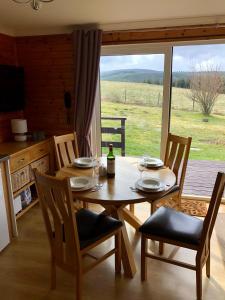 a wooden table with chairs and a bottle of wine on it at Ben Rinnes Lodge Glenlivet Highlands in Auchnastank