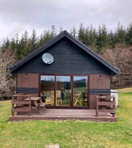 eine kleine Hütte mit einem großen Fenster und einer Holzterrasse in der Unterkunft Ben Rinnes Lodge Glenlivet Highlands in Auchnastank