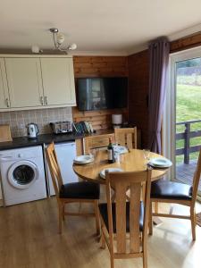 eine Küche mit einem Holztisch sowie einem Tisch und Stühlen in der Unterkunft Ben Rinnes Lodge Glenlivet Highlands in Auchnastank