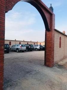 ein Backsteingebäude mit Autos auf einem Parkplatz in der Unterkunft Riad Dar Bab Todra in Tinghir