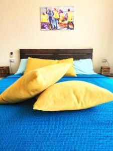a bed with yellow pillows and a blue blanket at Casa Bom Dia in Mindelo
