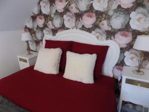 a bedroom with a red bed with two white pillows at Gîte des Marmouzeaux in Lemé