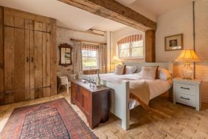 a bedroom with a bed and a table in a room at Heavenly luxury rustic cottage in historic country estate - Belchamp Hall Mill in Belchamp Otten