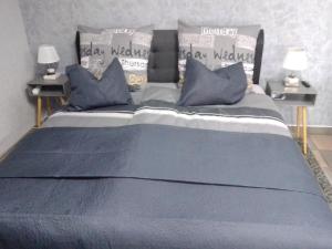 Una cama grande con sábanas azules y almohadas. en Orchideen Zimmer, en Wetzlar