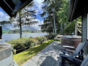 a house with a hot tub and chairs on a patio at Private Oceanfront Cabin With Hot Tub Doc Holiday Cabin in Ucluelet