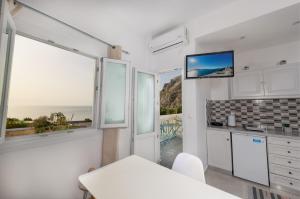 una cocina con armarios blancos y ventanas con vistas al océano. en Aislin House en Kamari