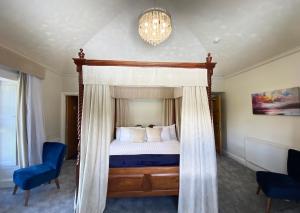 a bedroom with a canopy bed and a blue chair at Aberdunant Hall in Porthmadog