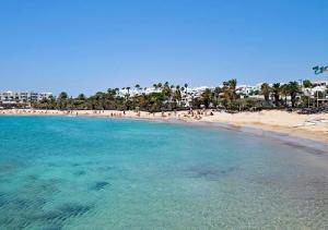 a beach with a bunch of people in the water at Villa Sun and sea 1 front de mer Playa Rocca Costa Teguise in Costa Teguise