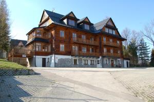 a large wooden building with a gambrel at Pałac Tatrzański Apartament Tatry in Bukowina Tatrzańska