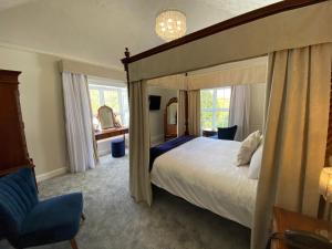 a bedroom with a canopy bed and a blue chair at Aberdunant Hall in Porthmadog