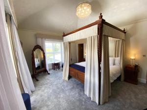 a bedroom with a canopy bed and a mirror at Aberdunant Hall in Porthmadog