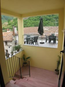 een balkon met een tafel en stoelen en een parasol bij B&B Il Vecchio Portale in Laino Borgo