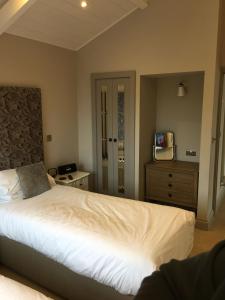 a bedroom with a bed and a dresser and a television at 5 Luxury Lodge with beautiful views of the Taf Estuary in Carmarthen