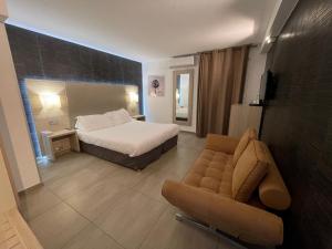 リル・ルッスにあるHôtel L'Escale Coté Portのベッドとソファのあるホテルの部屋
