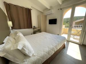 a bedroom with a large bed and a large window at Hôtel L'Escale Coté Port in LʼÎle-Rousse