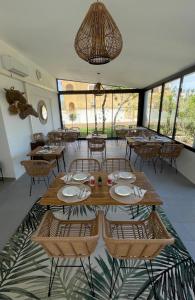 una sala da pranzo con tavoli, sedie e finestre di Hôtel L'Escale Coté Port a LʼÎle-Rousse