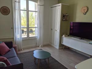 - un salon avec un canapé et une télévision dans l'établissement We Sea, à Deauville