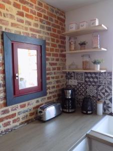 a kitchen with a counter with a toaster and a window at Gîte des Marmouzeaux in Lemé