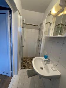 La salle de bains blanche est pourvue d'un lavabo et d'une douche. dans l'établissement Gästehaus zum Surgrund, à Cuxhaven