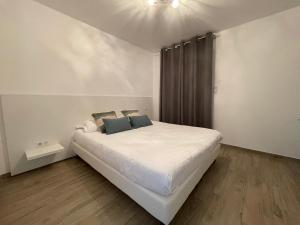 Schlafzimmer mit einem Bett mit weißer Bettwäsche und blauen Kissen in der Unterkunft Residence Des Îles in LʼÎle-Rousse