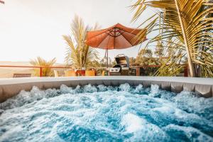 a jacuzzi tub with an umbrella on a patio at Natureza exuberante, conforto inesquecível, yurt mongol in Jacutinga