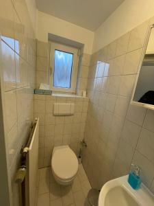 a bathroom with a toilet and a sink and a window at Gästehaus zum Surgrund in Cuxhaven