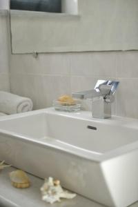 a white bathroom with a sink and a mirror at Chateau de Georges in Gythio