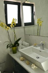 un baño con lavabo y un jarrón con flores. en Chateau de Georges, en Gythio