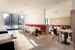 un restaurante con mesas y sillas y una gran ventana en Sorat Hotel Saxx Nürnberg en Núremberg