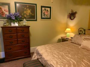 a bedroom with a bed and a dresser with flowers on it at Bayberry House Bed and Breakfast in Steubenville