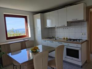 a kitchen with white cabinets and a table and a window at Bellevue in Marezige