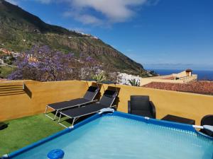 a swimming pool with chairs and the ocean in the background at Canarian House with views and pool in Los Realejos