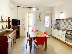 a kitchen with a wooden table and red chairs at Appartamenti Tina Paolini 1 piano terra con parcheggio in Castiglione della Pescaia