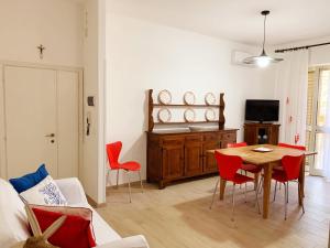 カスティリオーネ・デッラ・ペスカーイアにあるAppartamenti Tinaのリビングルーム(テーブル、赤い椅子付)