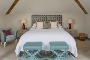 a bedroom with a large bed and a blue chair at The Barn in Devizes