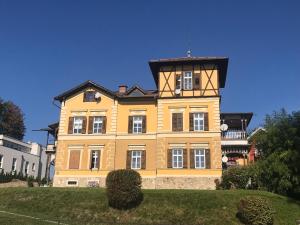 a large yellow building with a tower on top of it at Historische Villa Velden im Zentrum in Velden am Wörthersee