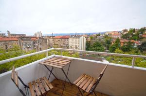 2 stoelen op een balkon met uitzicht op de stad bij Rijeka city rooms in Rijeka