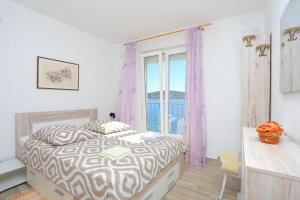 - une chambre avec un lit et une grande fenêtre dans l'établissement Apartments Delfin, à Rogoznica