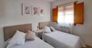 1 dormitorio con 2 camas, mesa y ventana en VUT Casa Orrios, en el centro de Alcañiz. en Alcañiz