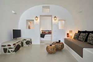 a white living room with a couch and a tv at Blue Art Caves in Oia