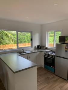 a kitchen with white counters and a refrigerator and windows at Palm Tree Villas in Rarotonga