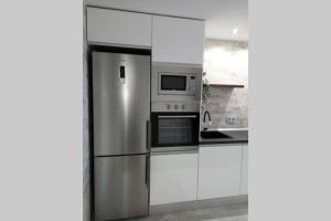 a kitchen with white cabinets and a stainless steel refrigerator at Loft Bazán - Centro Alicante in Alicante