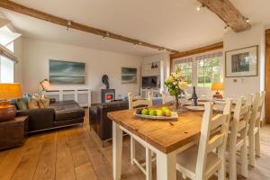 a kitchen and living room with a wooden table and chairs at Stylish luxury cottage in historic country estate - Belchamp Hall Coach House in Sudbury