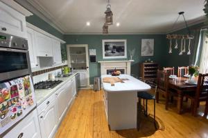 a kitchen with green walls and white cabinets and a table at Chemist's House in Cullen