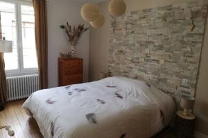 een slaapkamer met een wit bed en een bakstenen muur bij Gîte« Le Pressoir » chez viticulteur en biodynamie in Avenay-Val-dʼOr