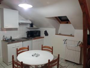 a small kitchen with a white table and a sink at Appartement 3 personnes tout équipé VOSGES. in Rochesson