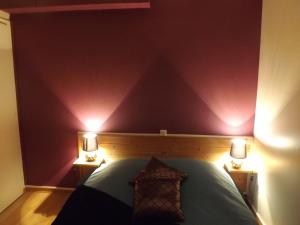 a bedroom with purple walls and a bed with two lights at Appartement 3 personnes tout équipé VOSGES. in Rochesson