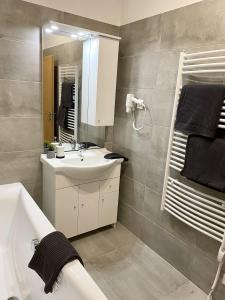 uma casa de banho com um lavatório, uma banheira e um espelho. em AquaLITA Apartman Zalakaros em Zalakaros