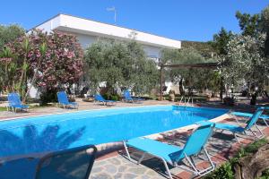 a swimming pool with blue chairs next to a building at VILLA IATROU in Potos