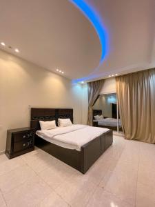 una camera da letto con un grande letto e una luce blu sul soffitto di فيلا هابي نايت a Al Shafa